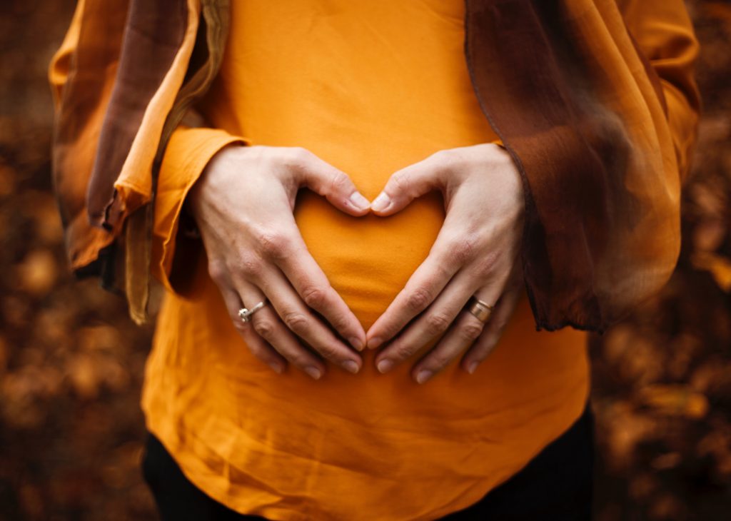 woman making a heart out of her hands over her pregnant stomach