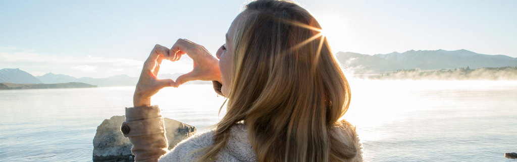 Women standing and making a heart shape with hands.