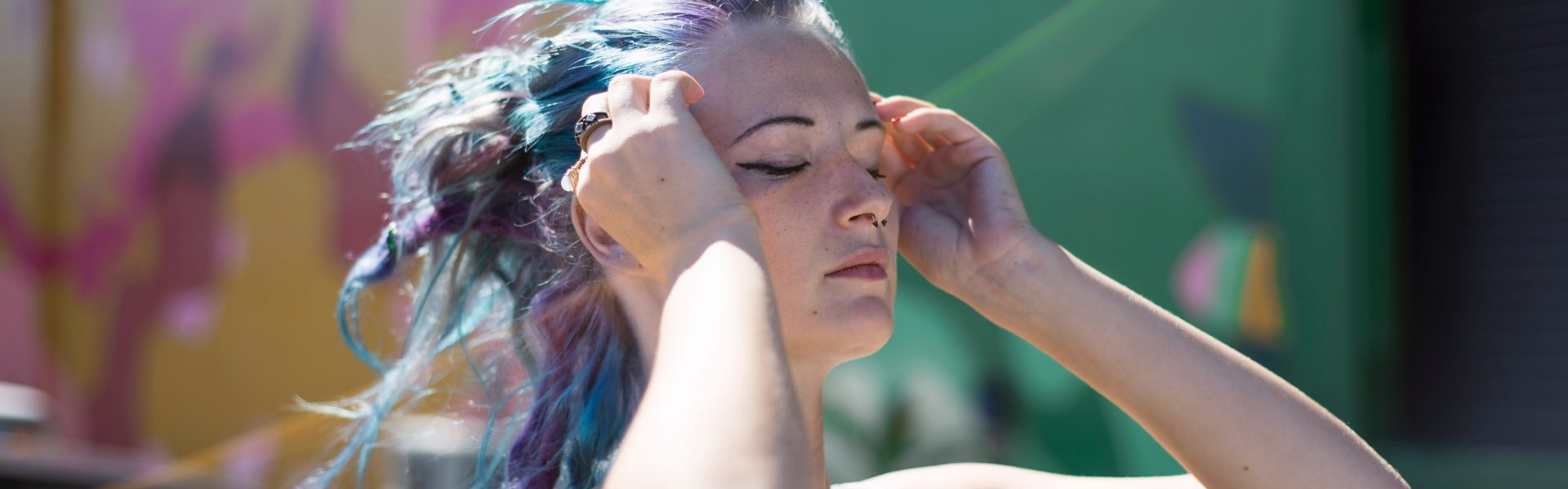woman with purple hair holding fingers to temples