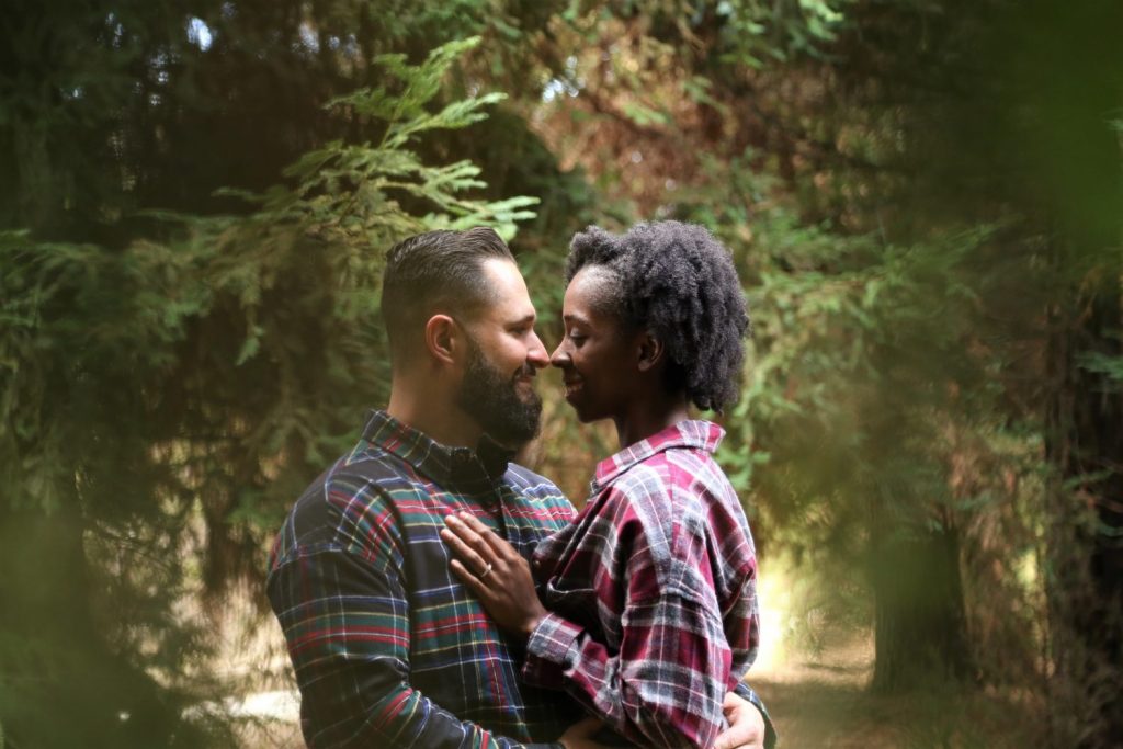 Man and woman wearing button-up sports shirt on the center of trees.