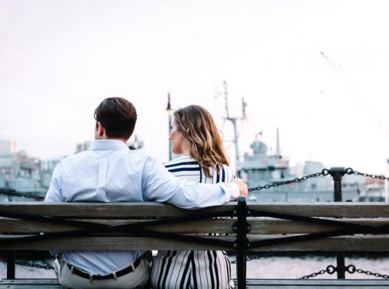 couple sitting on bench near body of water