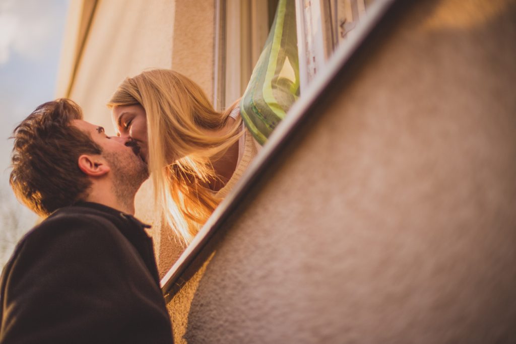 Lovely couple kissing on window at sunny day