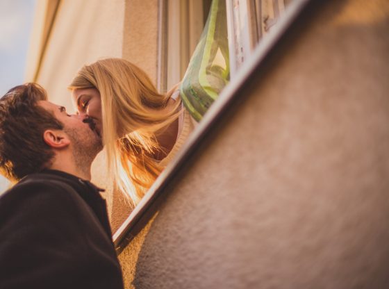Lovely couple kissing on window at sunny day
