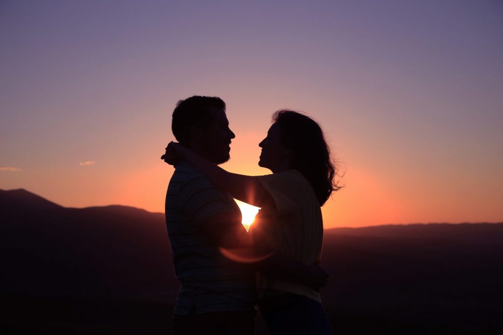 Couple holding each other while the sun comes.