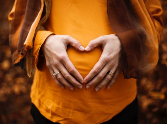 woman making a heart out of her hands over her pregnant stomach