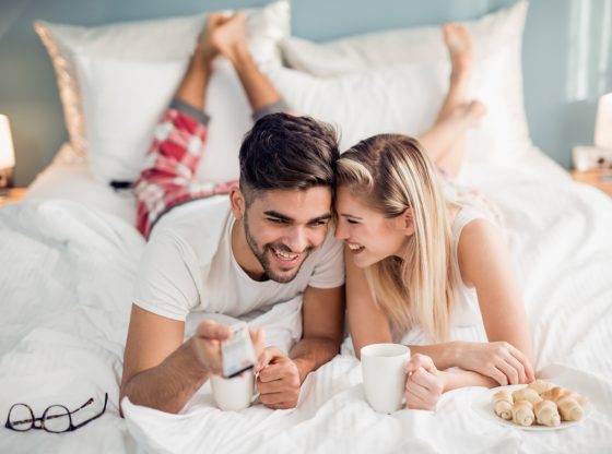 Young couple waking up and watching TV