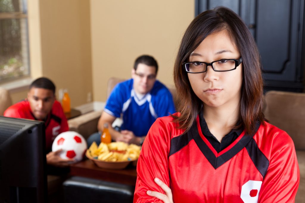 Young woman upset at men watching sports on TV