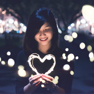 Female holding a light shaped as a heart.