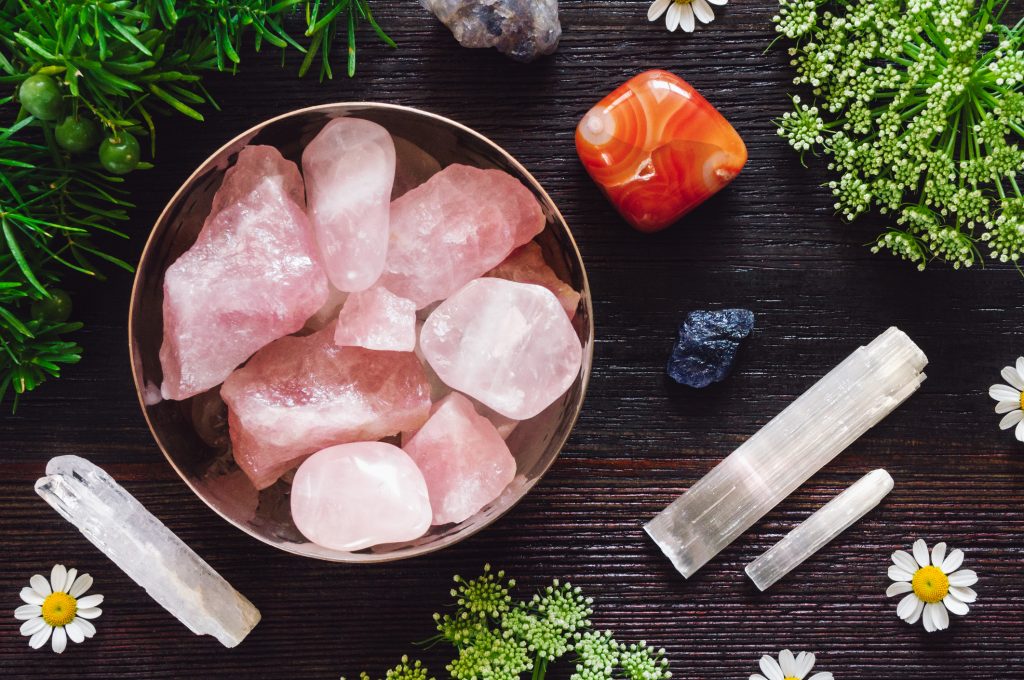 flatlay of rose quartz, crystals and flowers