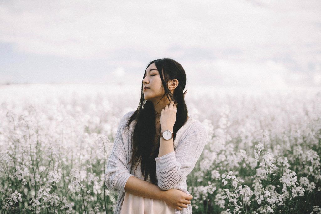 east asian woman standing in field of white flowers