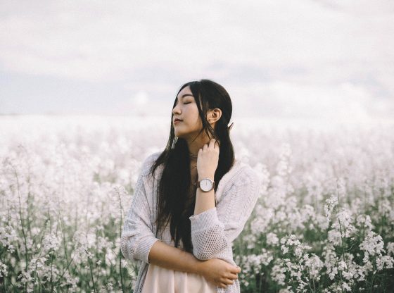 east asian woman standing in field of white flowers
