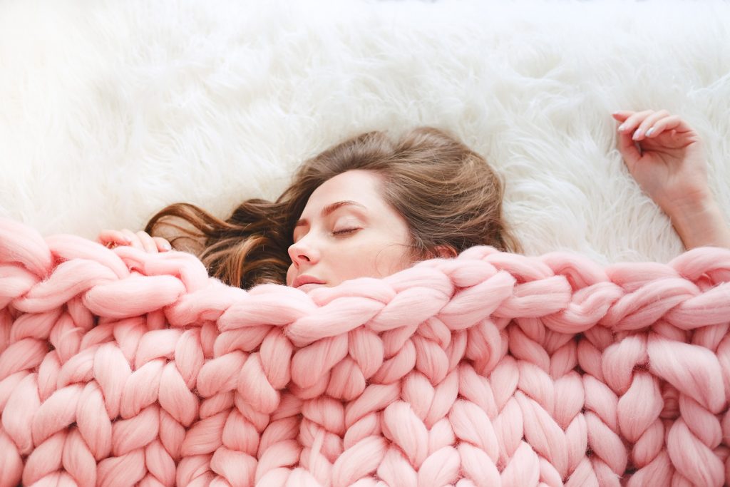 woman sleeping under knitted blanket