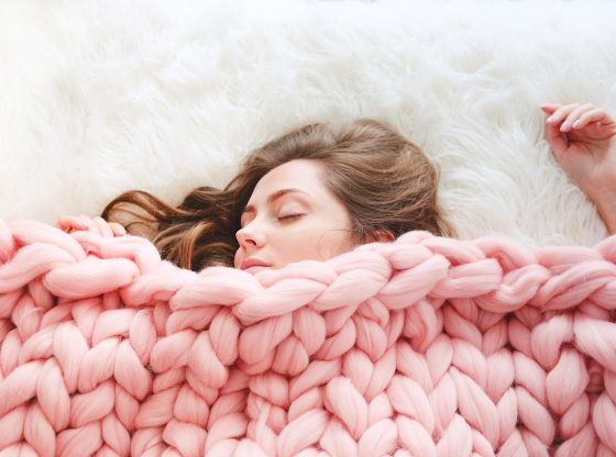 woman sleeping under knitted blanket