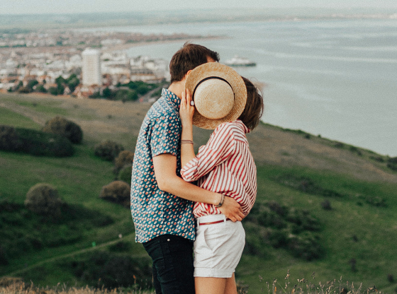 couple kissing behind hat