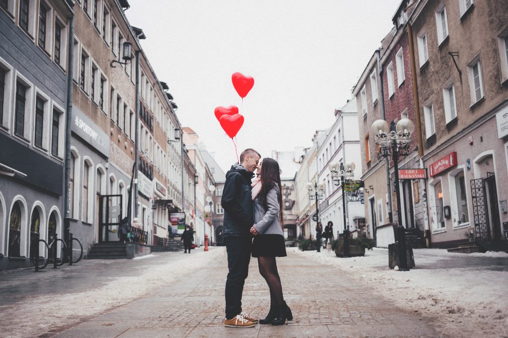 couple kissing with heart balloons
