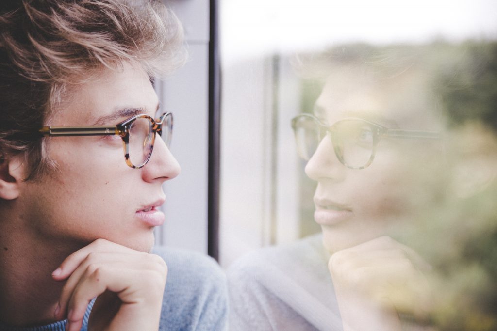 Man with glasses looking out window