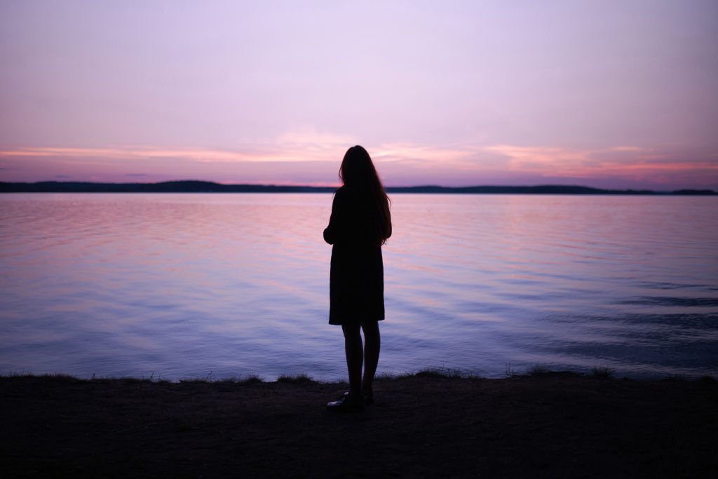 silhouette of woman looking out at lake