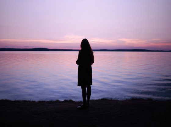 silhouette of woman looking out at lake