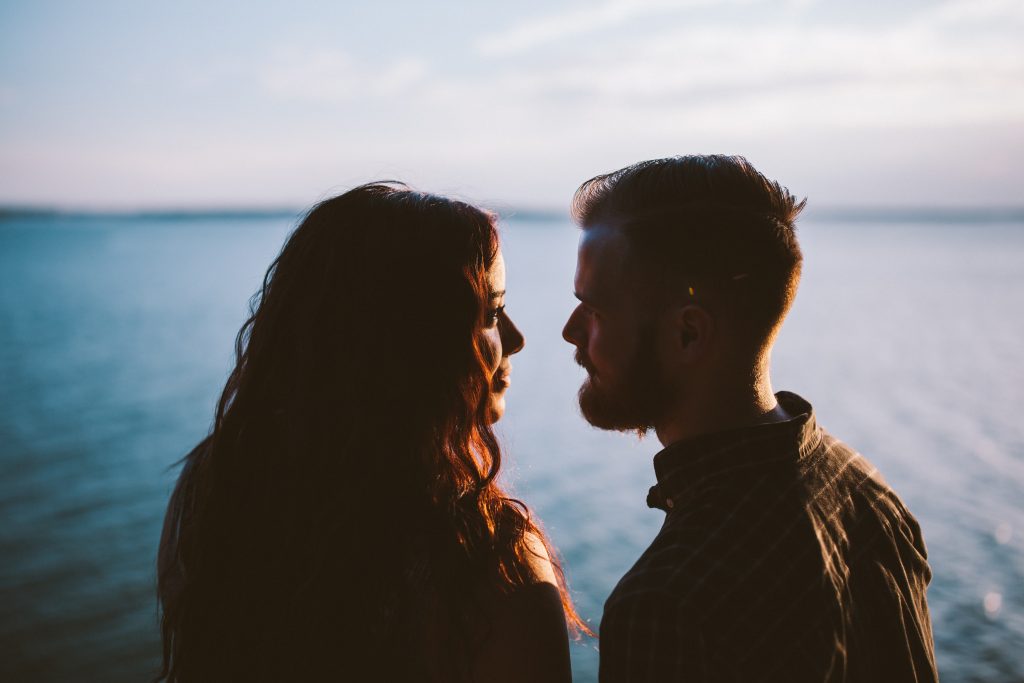 couple looking into each other's eyes near ocean