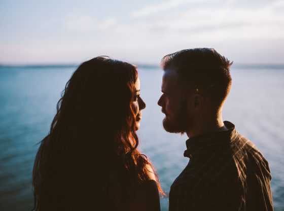 couple looking into each other's eyes near ocean