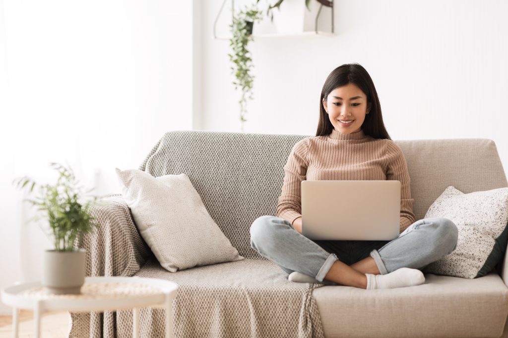 woman sitting cross-legged on couch with laptop