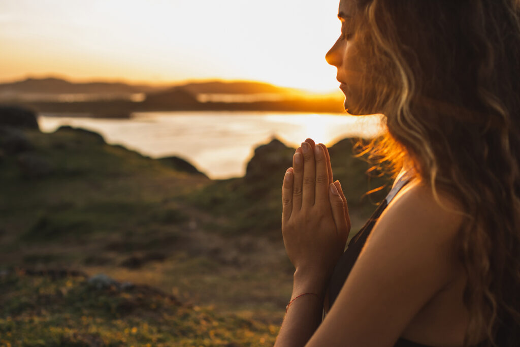Spiritual Woman praying alone at sunrise. Nature background. Spiritual and emotional concept. Sensitivity to nature