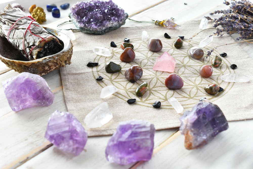 A close up image of a self love crystal grid using the flower of life sacred geometry grid cloth and amethyst crystals.