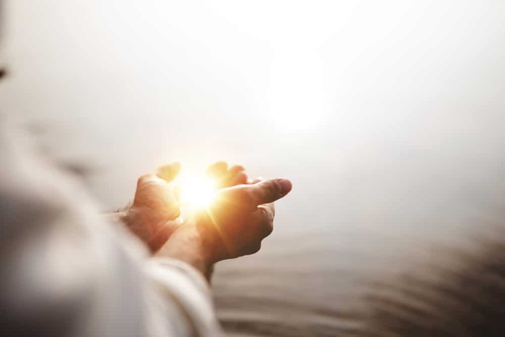 A man’s hands holding a light that symbolizes divine guidance