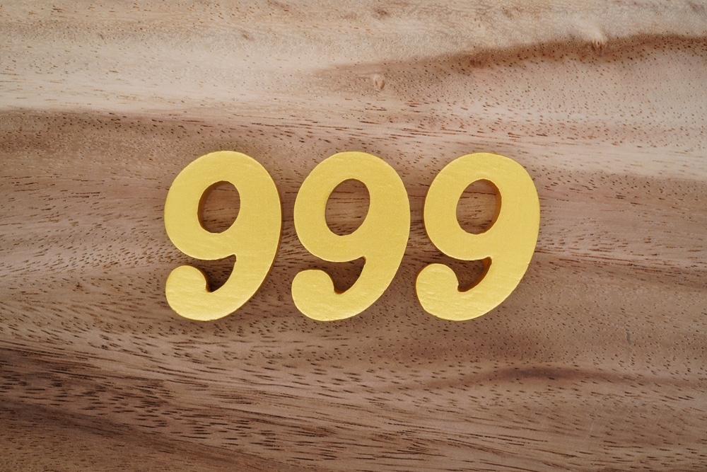 Number 999 in yellow on brown wood background.