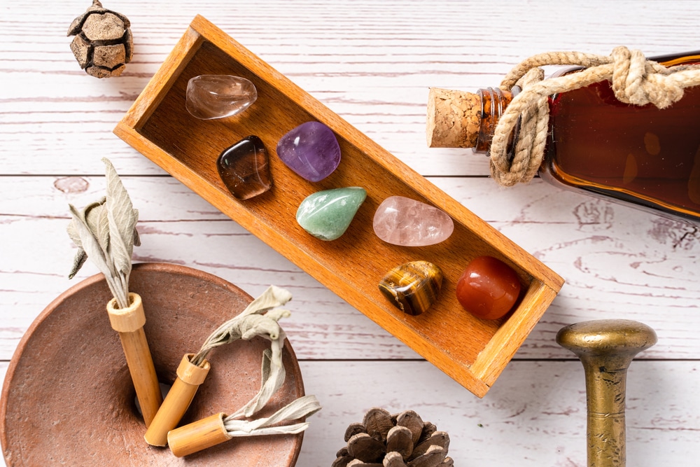 Top view on seven chakra healing crystal stones for mind body and soul and bottle with aromatic essential oils on wooden table