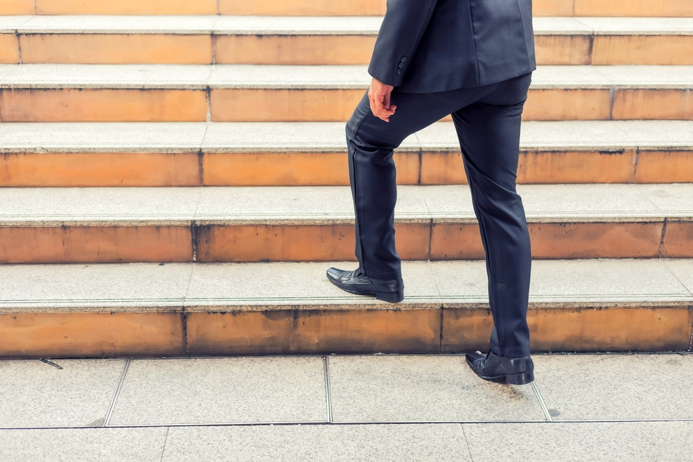 Cropped image of businessman walking up the stairs to success.