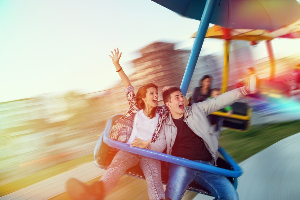 A couple laughing on a ride at an amusement park.