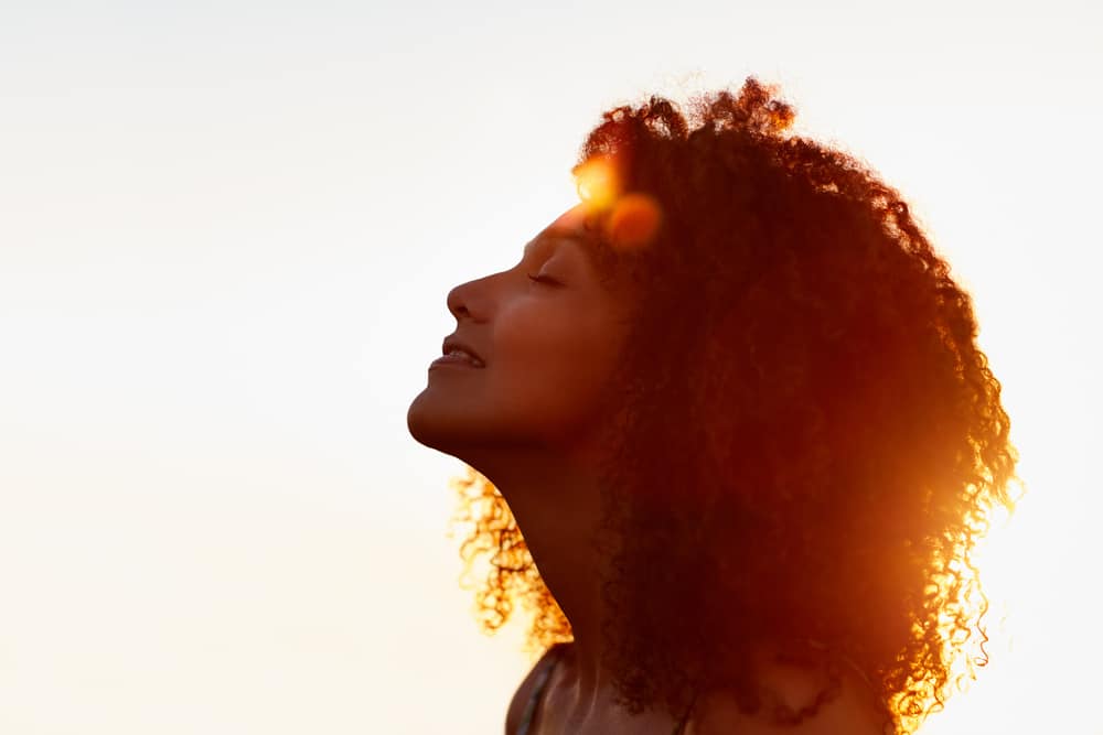 A psychic woman with closed eyes smiles and looks up.