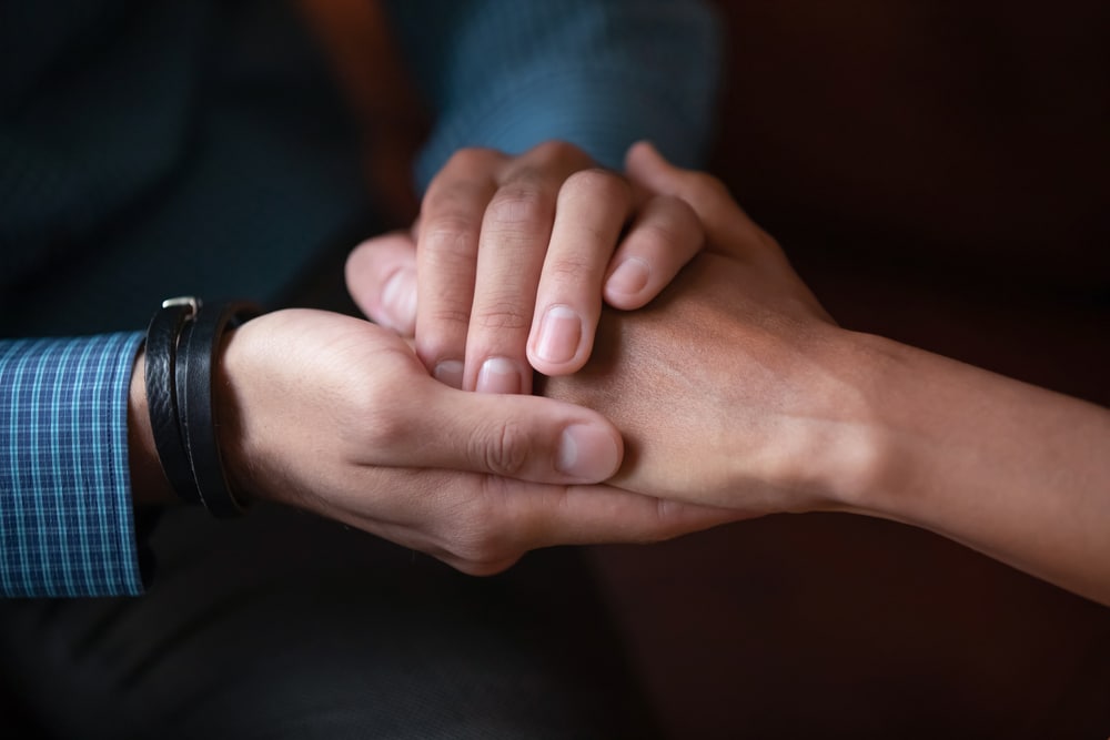 Close up of empathic people holding hands.
