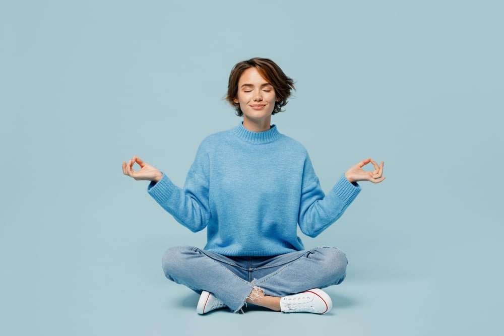 A meditating woman wearing blue in a blue room